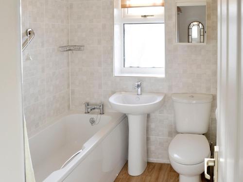 a bathroom with a sink and a toilet and a bath tub at Heron's Quay in Wroxham