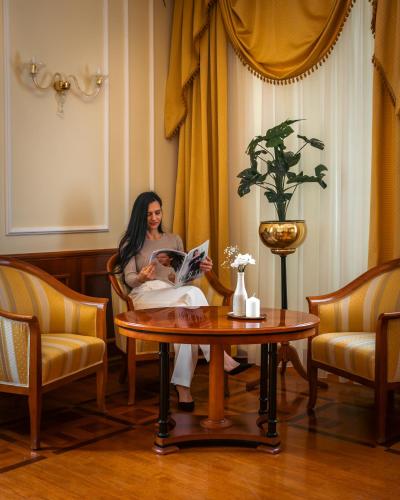 a woman sitting in a chair reading a magazine at Dvorec Jeruzalem in Ivanjkovci