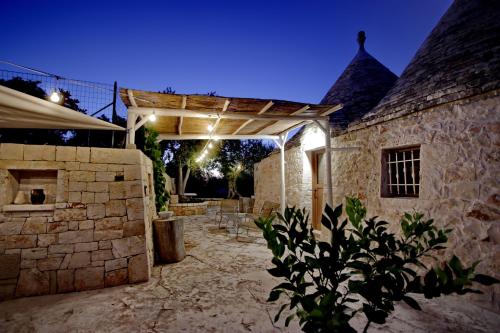 an outdoor patio with a stone wall and a wooden pergola at Trullo San Giovanni in Castellana Grotte