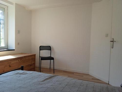 a bedroom with a chair and a bed and a dresser at Le duplex d'Abi in Saint-Étienne