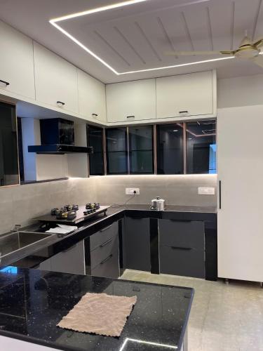 a large kitchen with black counters and white cabinets at Peaceful Private Residence in Hyderabad