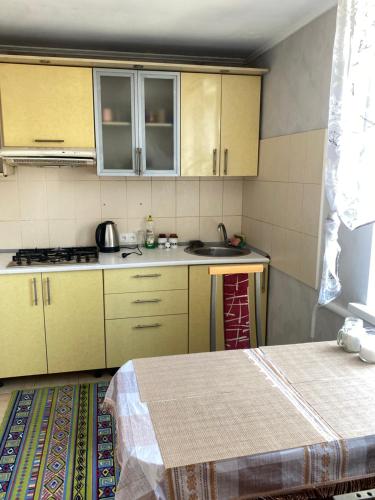 a small kitchen with yellow cabinets and a table at Сдам две комнаты возле моря in Odesa