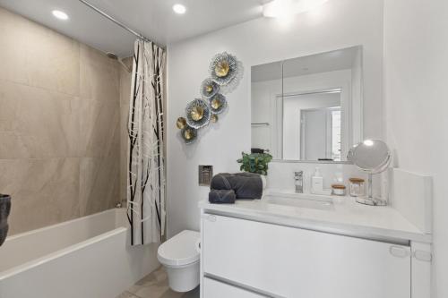バンクーバーにあるModern 3BR Condo with Rooftop, Gym and Parking near Skytrainの洗面台、トイレ、鏡のあるバスルーム