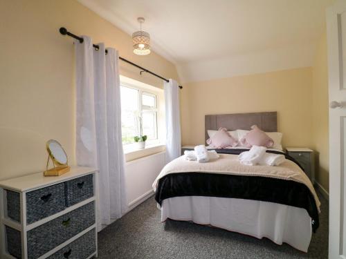 a bedroom with a bed with pink pillows and a window at Oxcroft View in Worksop