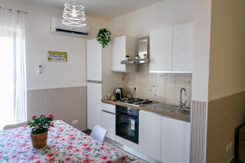 a kitchen with white cabinets and a table with a plant at Mare Blu in Giardini Naxos