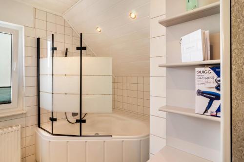 un bagno con doccia e piastrelle bianche di Ferienwohnung an der Ohme a Warburg