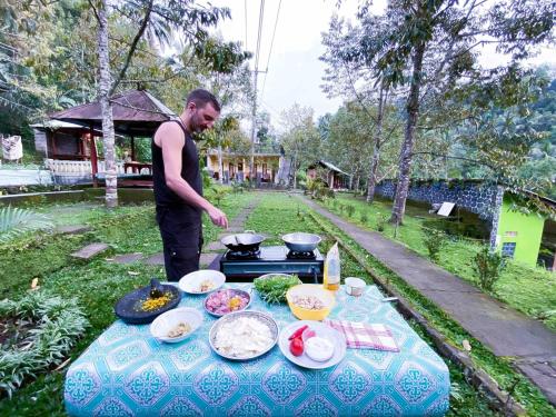a man standing next to a table with food on it at Ananda Homestay in Singaraja