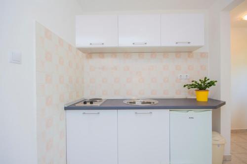 a kitchen with white cabinets and a sink at Pula Istria Apartments in Pula