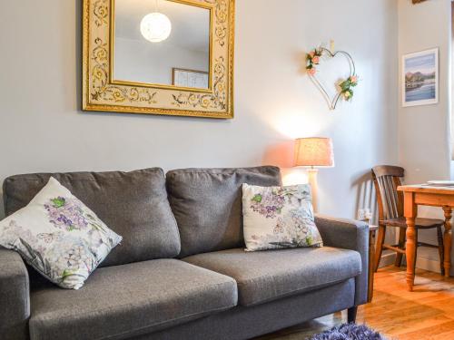 a living room with a couch and a mirror at Pollywiggle Cottage in Keswick