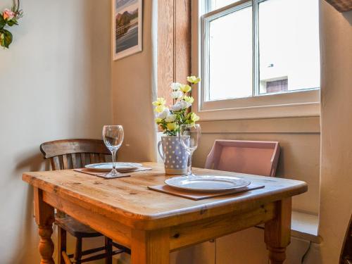 a wooden table with two plates and a vase of flowers at Pollywiggle Cottage in Keswick