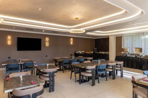 a restaurant with tables and chairs and a flat screen tv at Nobel West Hotel in Belgrade