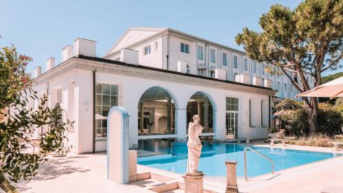 a woman standing next to a swimming pool in front of a building at Bellavista Terme Resort & Spa in Montegrotto Terme