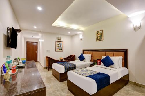 a hotel room with two beds and a desk at Airport La Sapphire Hotel & Restaurant in New Delhi