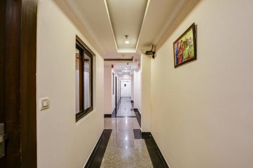 a hallway with white walls and black and white tile floors at Airport La Sapphire Hotel & Restaurant in New Delhi
