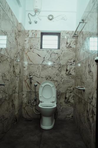 a bathroom with a toilet and a stone wall at Saras Lodge in Cochin