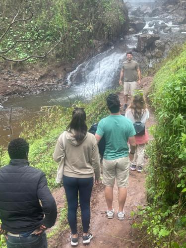 a group of people walking down a trail near a waterfall at Local Villa Lodge in Arusha