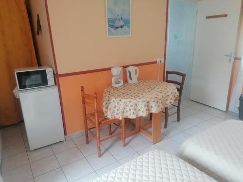 Il comprend une petite cuisine avec une table, des chaises et un four micro-ondes. dans l'établissement Le Clos des roses, à Civray-de-Touraine