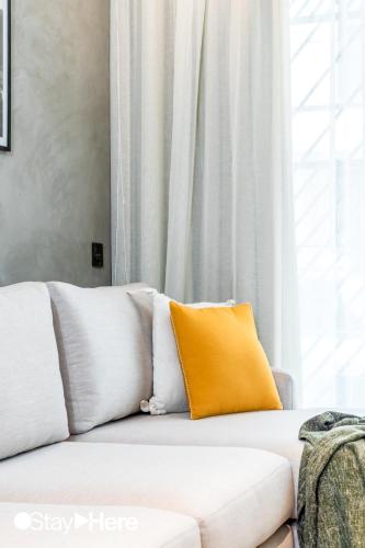a white couch with an orange pillow on it at Stayhere Casablanca - Gauthier 1 - Modern Residence in Casablanca
