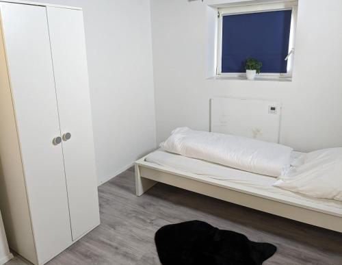 a white bedroom with a bed and a window at Handwerker Wohnung im Landhaus in Ramhusen