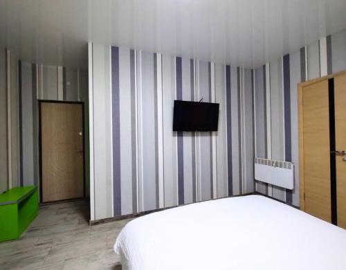 Un dormitorio con una cama y un televisor en la pared. en Безпечні апартаменти на цокольному поверсі біля метро, en Járkov