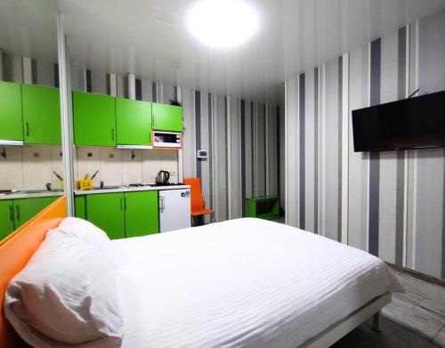 Un dormitorio con armarios verdes y una cama blanca. en Безпечні апартаменти на цокольному поверсі біля метро, en Járkov