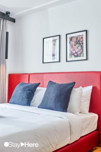a bed with a red headboard and blue pillows at Stayhere Casablanca - Gauthier 1 - Modern Residence in Casablanca