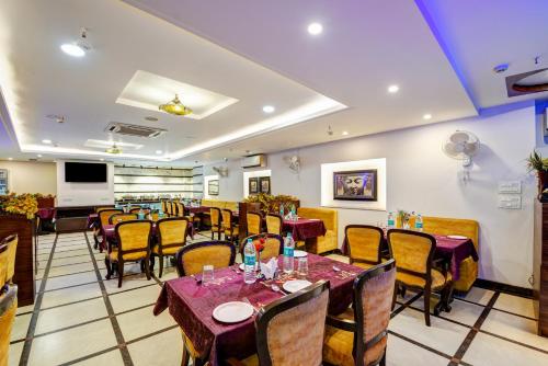 a restaurant with tables and chairs in a room at Airport La Sapphire Hotel & Restaurant in New Delhi