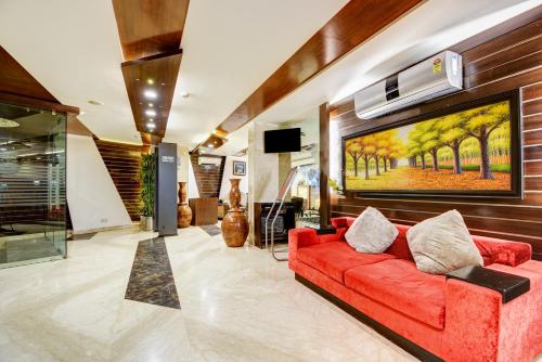 a living room with a red couch and a painting on the wall at Airport La Sapphire Hotel & Restaurant in New Delhi