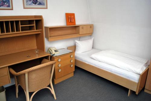 バート・ザルツフレンにあるHostel am Gartenのベッドとデスクが備わる小さな客室です。