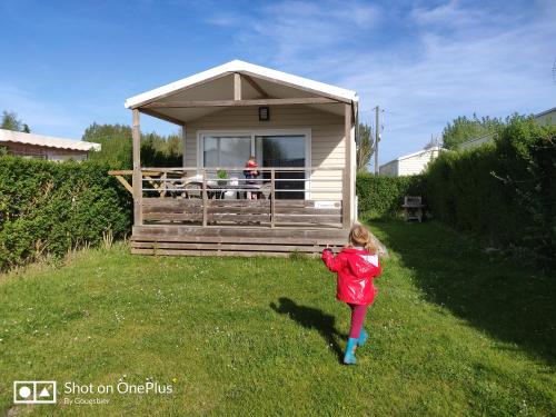 a little girl standing in front of a small house at CAMPING DES OISEAUX- Baie de Somme in Rue