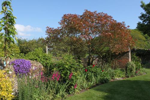 a garden with colorful flowers and a brick wall at B&B South Downs Way in Poynings
