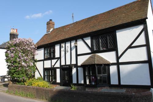 an old black and white building with a tree at B&B South Downs Way in Poynings