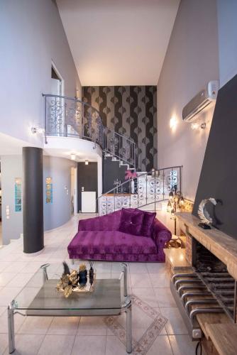 a living room with a purple couch and a staircase at Dana's Luxury Maisonette in Volos