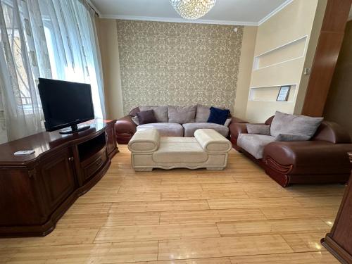 a living room with a couch and a flat screen tv at Апартаменты на Назарбаева 44 in Karagandy