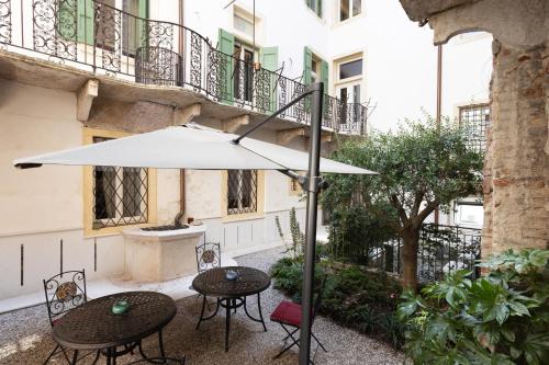 un patio con due tavoli e un ombrellone di Palazzo Reggiani - Maria Callas a Verona
