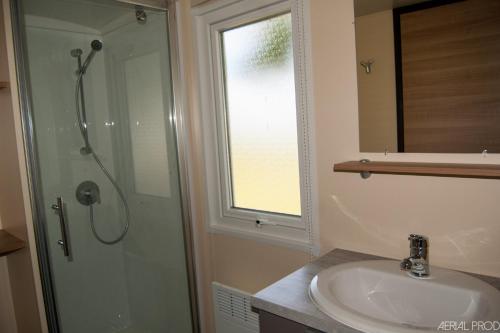 a bathroom with a shower and a sink and a mirror at CAMPING DES OISEAUX- Baie de Somme in Rue