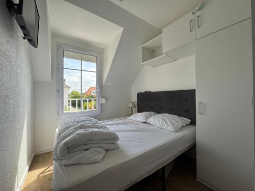 une chambre avec un lit avec des draps blancs et une fenêtre dans l'établissement L'Eclipse, à Fort-Mahon-Plage
