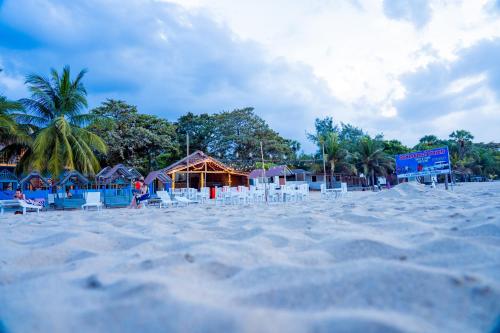 a sandy beach with chairs and buildings and palm trees at Golden Beach Hotel & Restaurant in Trincomalee
