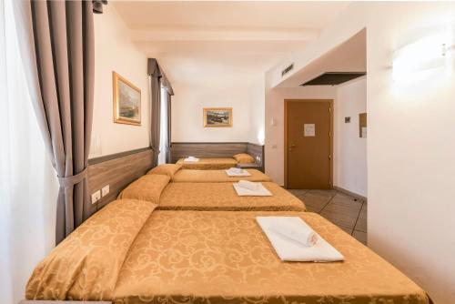 a row of four beds in a room at Hotel Brianza in Milan