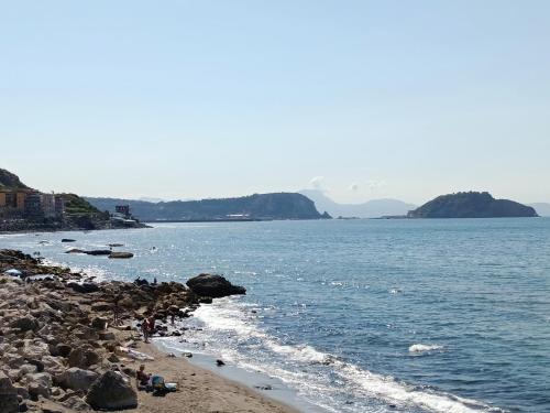 a group of people sitting on a beach near the water at TIVA' Holiday House in Pozzuoli
