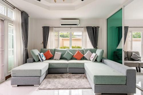 a living room with a green couch and orange pillows at Kevin's Pool Villa at Chiang Mai - 4BDR 4Bath Airport & Old City 5min in Chiang Mai