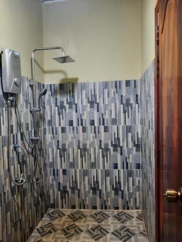 a bathroom with a shower with a tiled wall at Joes Homestay in Siem Reap