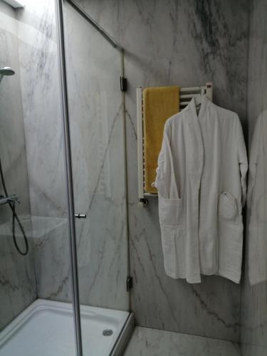 a bathroom with a shower and a white robe on a towel at Sunny Ofir in Fão