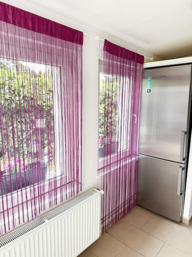 a kitchen with a window with purple curtains and a refrigerator at Juicy Private Apartments with Jacuzzi in Szentendre