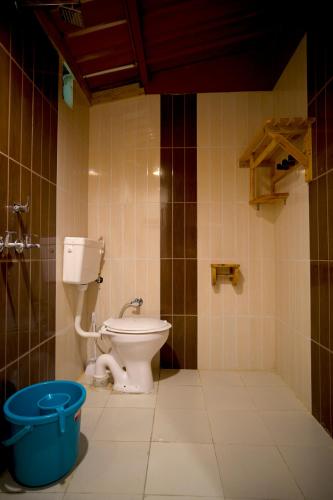 a bathroom with a toilet and a blue bucket at Sparrow Woods Eco Resort in Nainital