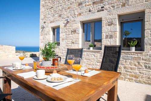 a wooden table with food and wine glasses on a patio at Villa Sofita Komos View in Pitsidia