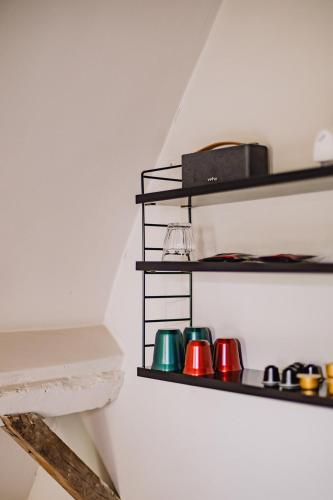 a shelf with four different colored cups on a wall at Burgstraat 8 in Ghent