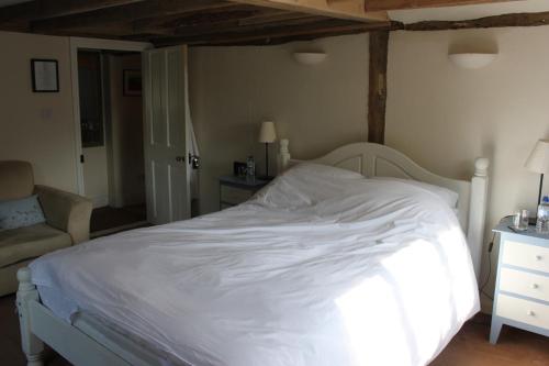 a bedroom with a white bed and a chair at B&B South Downs Way in Poynings