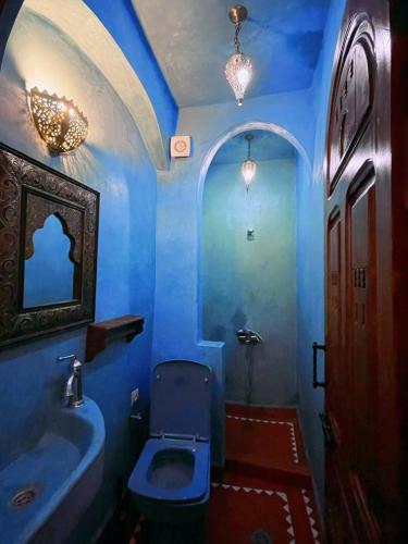 a blue bathroom with a toilet and a sink at Riad Bab Mahrouk in Chefchaouene