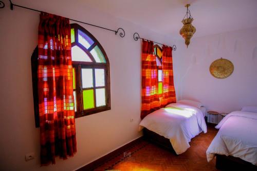 a bedroom with two beds and a window at Riad Bab Mahrouk in Chefchaouene